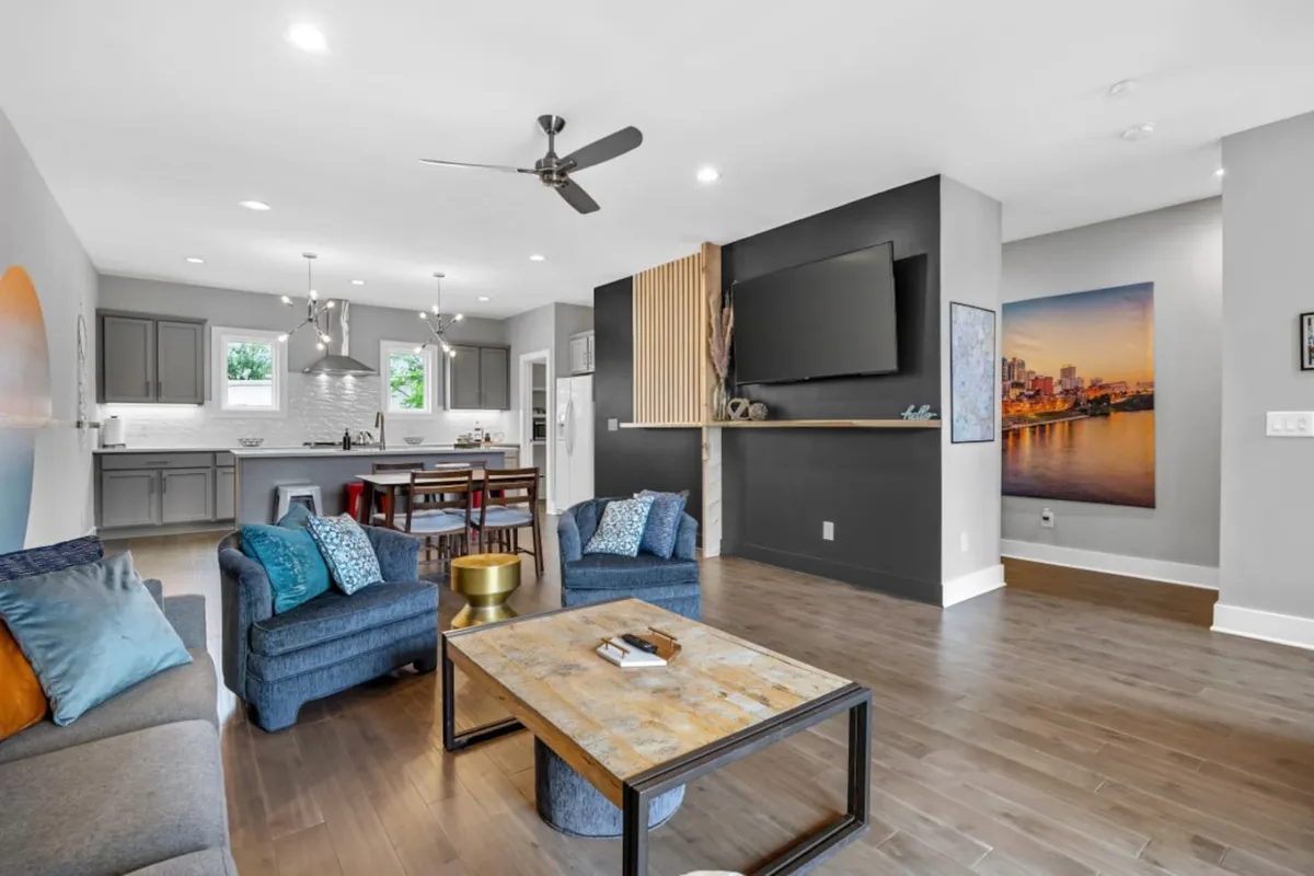 The image showcases a stylish, open-concept living space with a plush seating area, a modern dining table, and a sleek kitchen island—all set in a contemporary, light-filled interior adorned with tasteful artwork. The layout invites relaxation and connection, ideal for socializing, sharing meals, or enjoying a cozy movie night with friends and family.