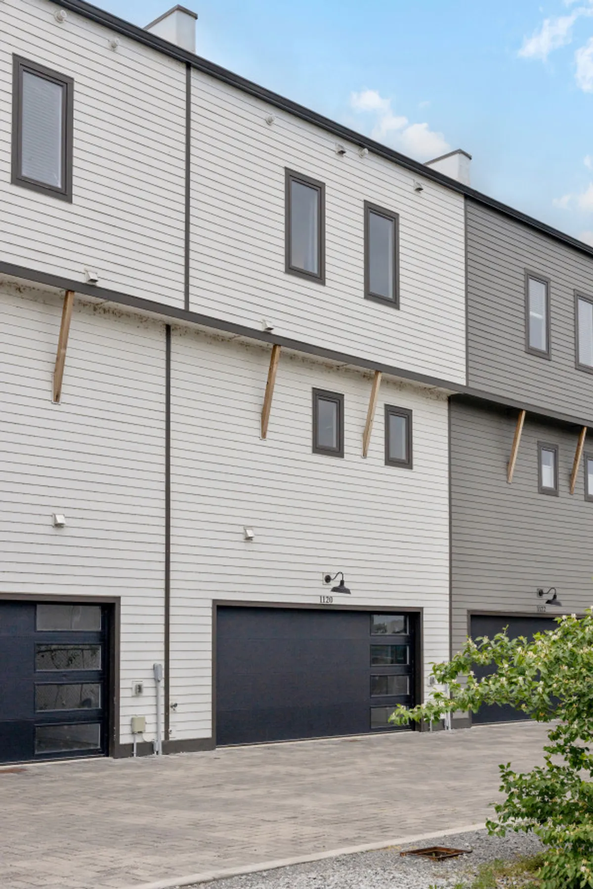 An exterior shot showcasing the townhouse's modern architectural design, emphasizing the clean lines of the garage doors and the inviting facade. The image captures both the private entry and a sense of contemporary exclusivity.