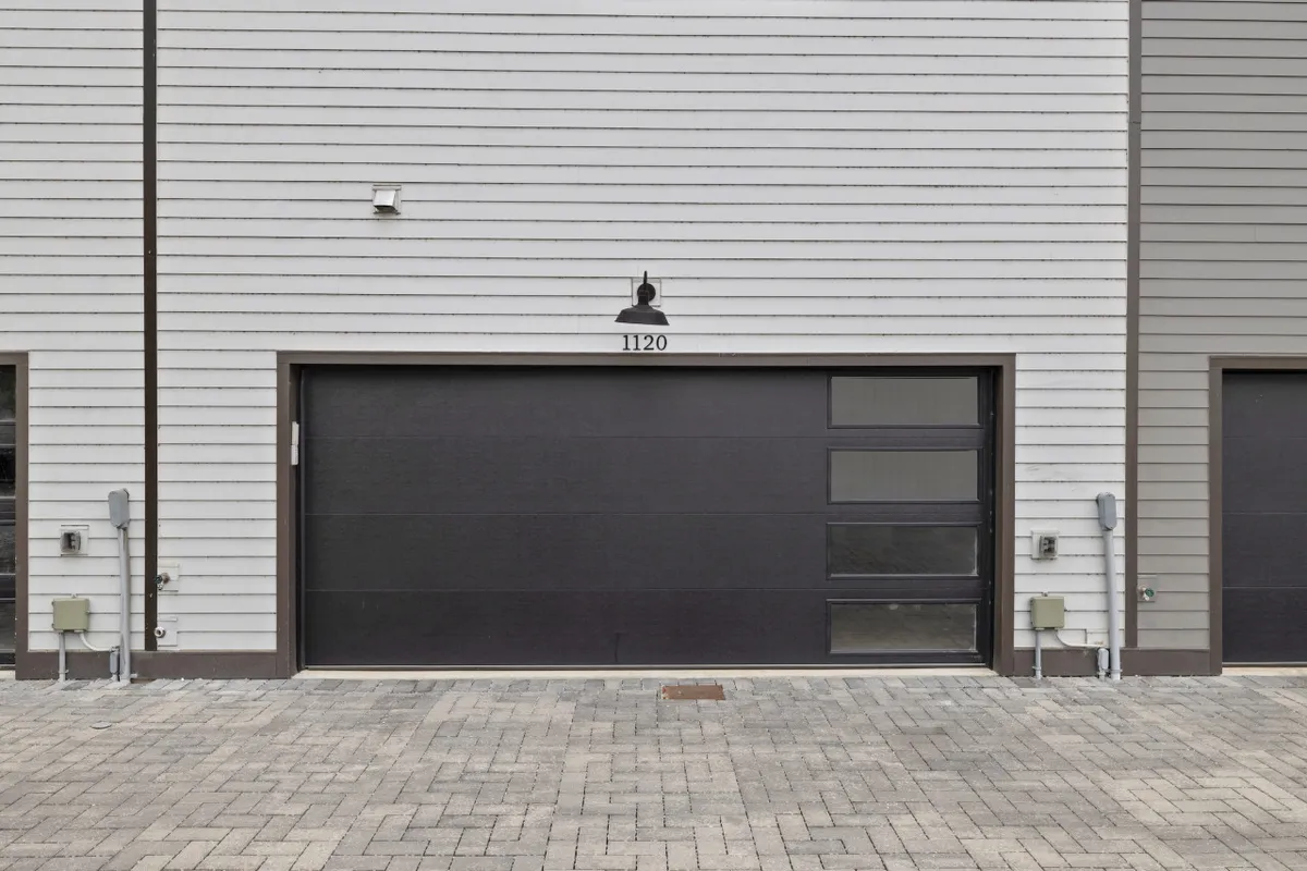 This image focuses on the home's exterior garage door, prominently displaying the house number and a lighting fixture above. The clean and organized lines emphasize the functional convenience of the private, attached garage.